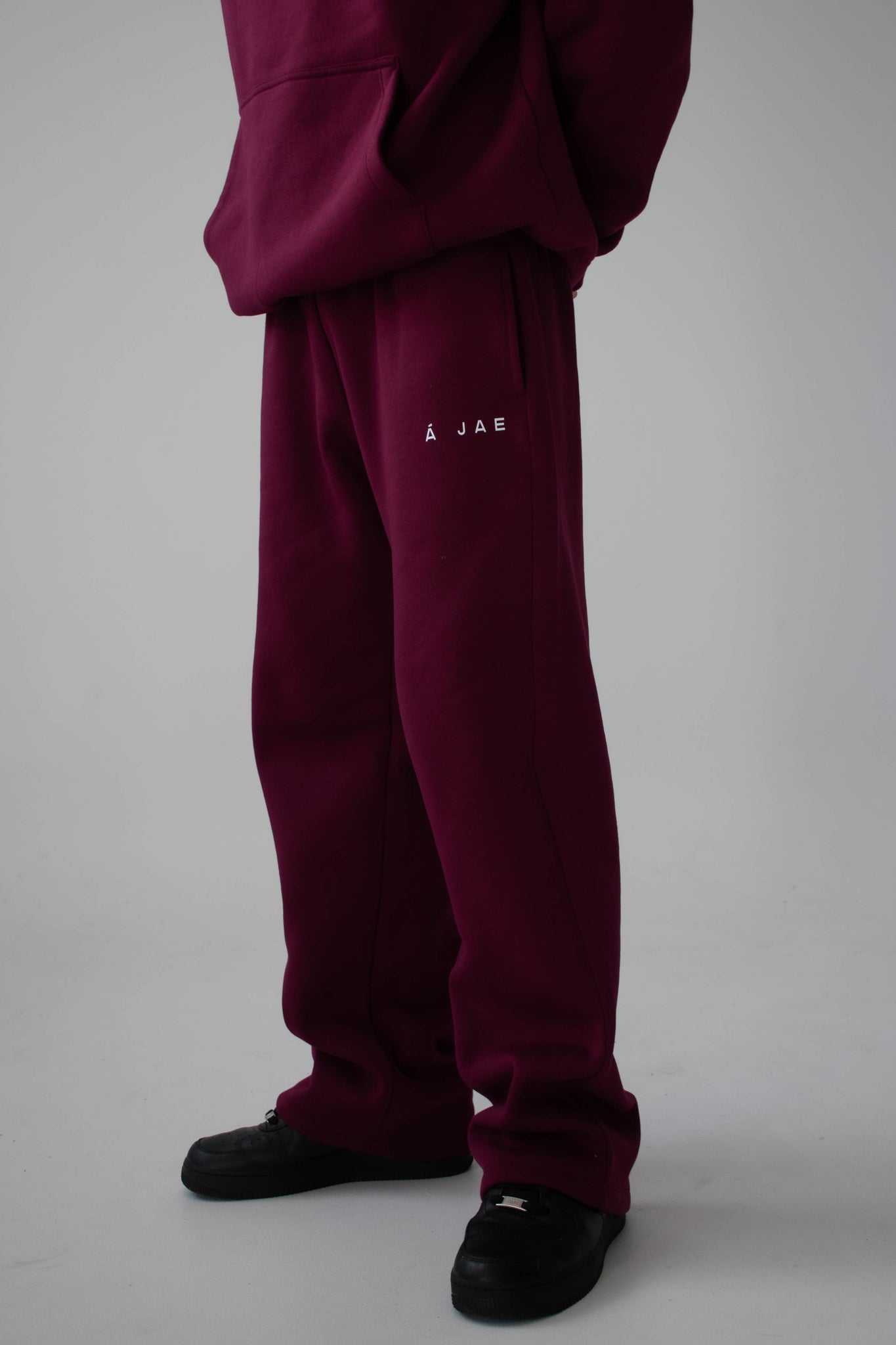 burgundy tracksuit with a logo on a grey background