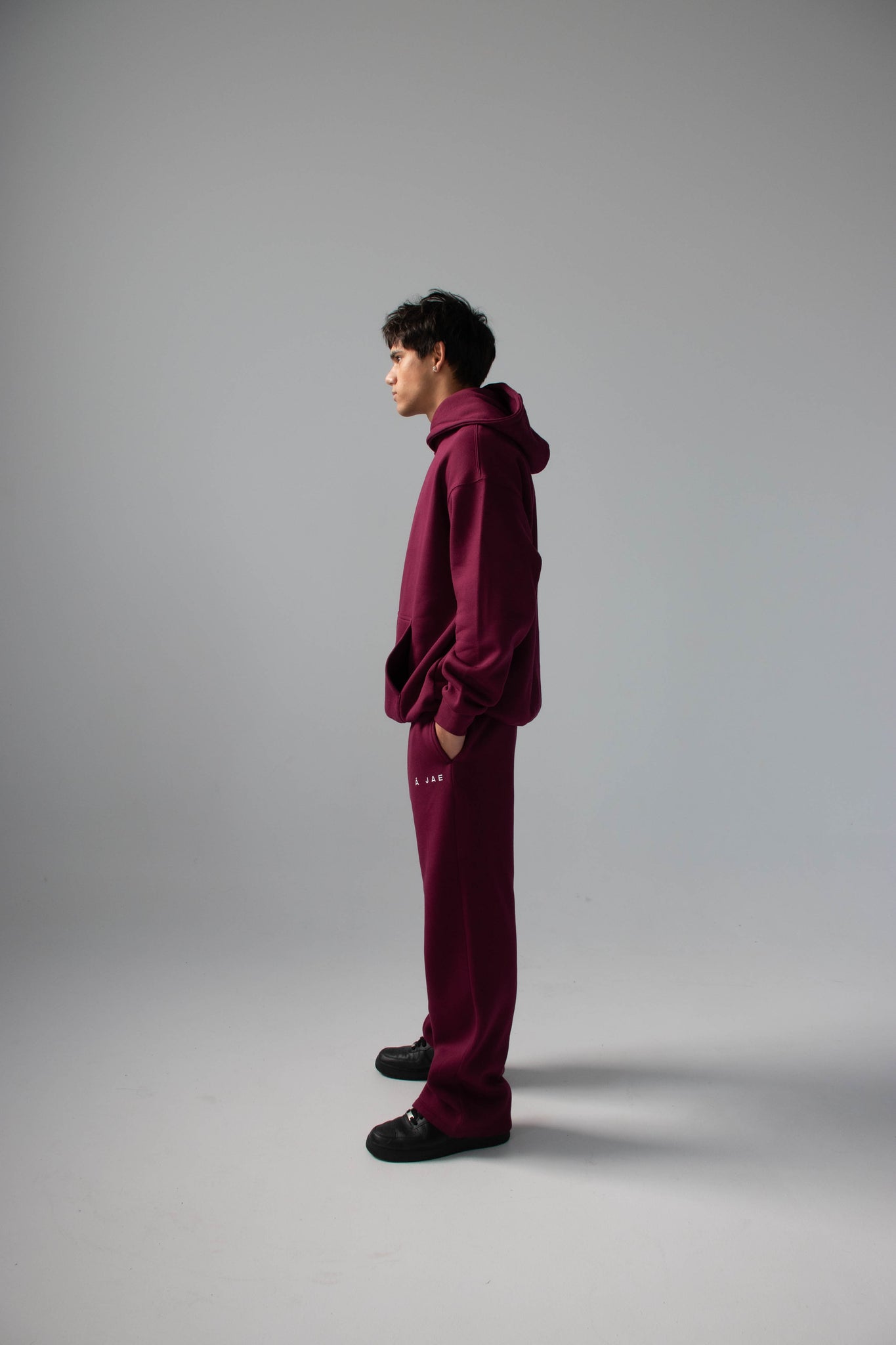 Person wearing a burgundy tracksuit standing against a plain background